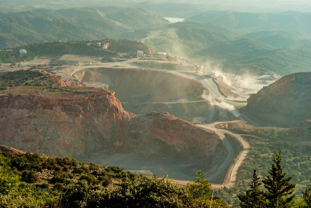 Vue aérienne de la carrière minière à ciel ouvert avec beaucoup de machines au travail - vue d'en haut. pierres de carrière, pour construction avec ciel bleu. environnement minier, contexte de l'industrie. paysage rural,