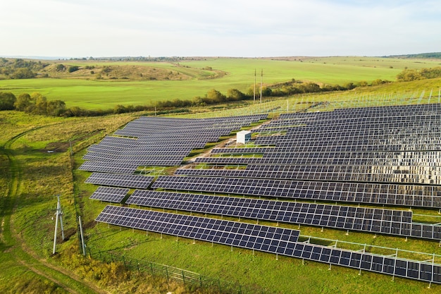 Vue aérienne de la centrale solaire en construction sur champ vert. Assemblage de panneaux électriques pour la production d'énergie écologique propre.