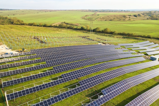 Vue aérienne de la centrale solaire en construction sur champ vert. Assemblage de panneaux électriques pour produire une énergie écologique propre.