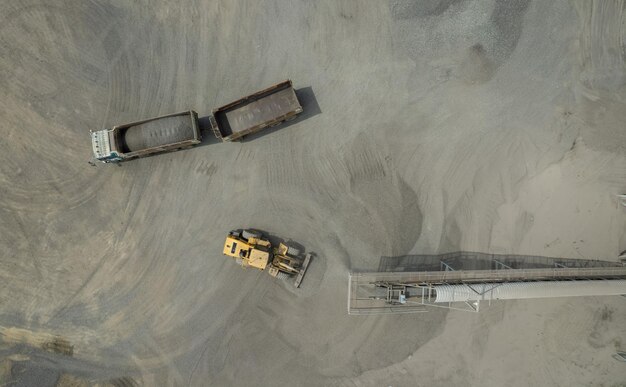 Vue aérienne de chargeurs de sable pelletant des roches dans des camions à benne basculante