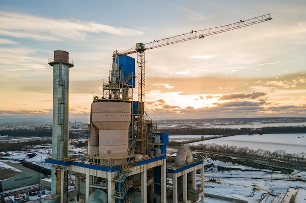 Vue aérienne de la cimenterie avec une structure d'usine élevée et une grue à tour dans la zone de production industrielle.