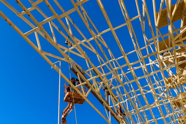 Vue aérienne d'un constructeur sur le toit inachevé avec des poutres en bois clouées dans la maison de charpente sous