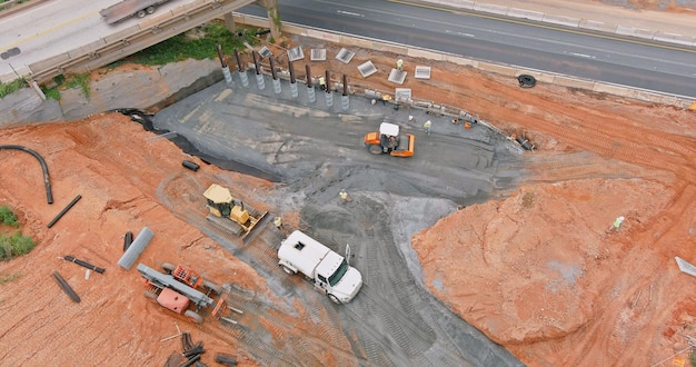 Vue aérienne de la construction d'une autoroute surélevée en cours, les travailleurs et la machinerie lourde se joignent