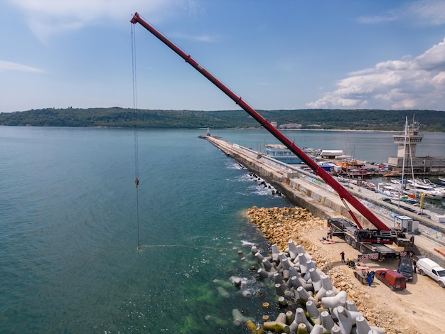 Vue aérienne de la construction de brise-lames Bulldozer et grue sur un tas de rochers dans la mer