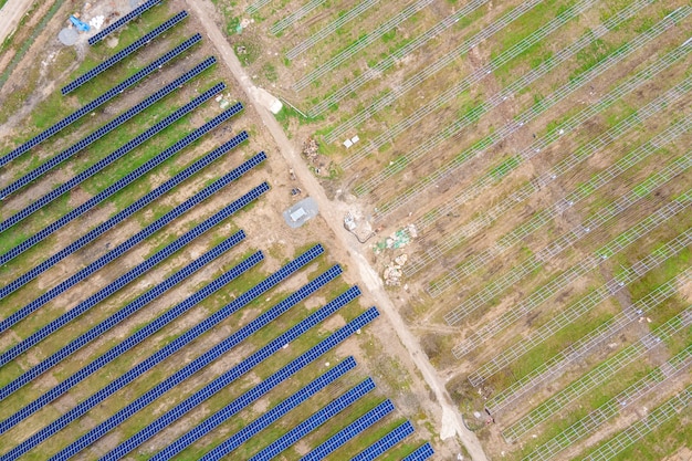 Vue aérienne de la construction d'une grande centrale électrique avec de nombreuses rangées de panneaux solaires sur châssis métallique pour produire de l'énergie électrique écologique propre. Développement des sources d'électricité renouvelables.