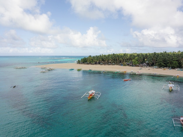 Vue aérienne d'une côte océanique avec plage de sable et quelques bateaux dans l'eau