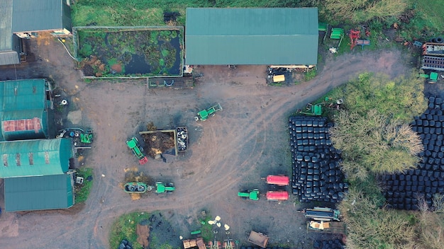 Vue aérienne d'une cour de ferme en activité avec des tracteurs et des granges industrielles