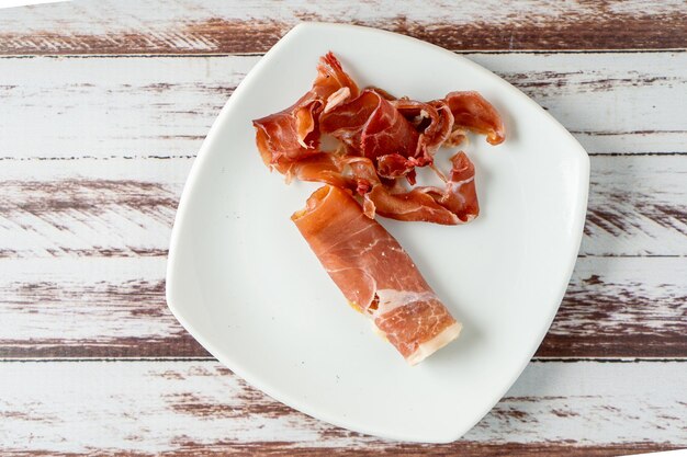 Vue aérienne d'un délicieux jambon serrano espagnol sur une assiette blanche.