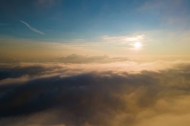 Vue aérienne depuis la fenêtre de l'avion à haute altitude de denses cumulus gonflés se formant avant la pluie en soirée.