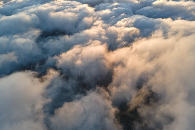 Vue aérienne depuis la fenêtre de l'avion à haute altitude de denses cumulus gonflés volant en soirée