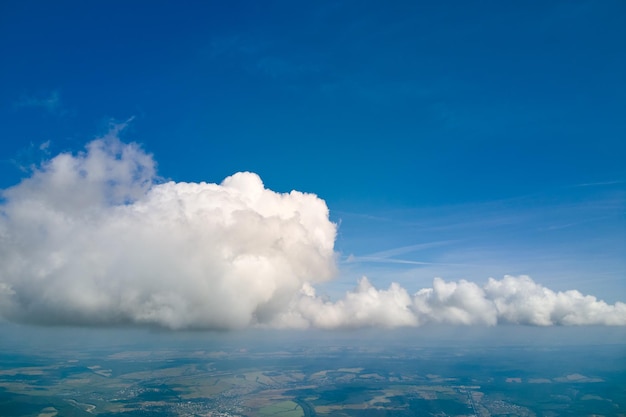 Vue aérienne depuis la fenêtre de l'avion à haute altitude de la terre recouverte de cumulus blancs gonflés.