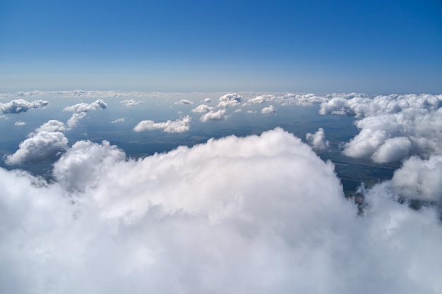 Vue aérienne depuis la fenêtre de l'avion à haute altitude de la terre recouverte de cumulus blancs gonflés.