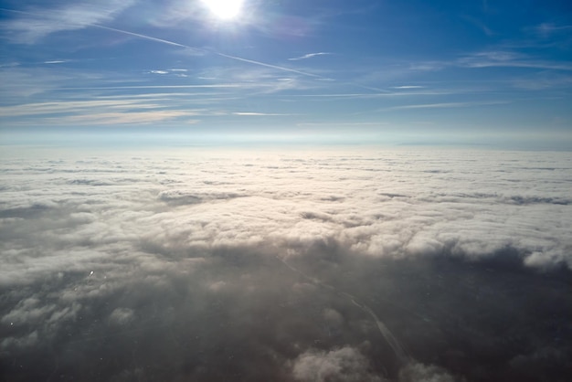 Vue aérienne depuis la fenêtre de l'avion à haute altitude de la ville lointaine recouverte d'une fine couche de smog brumeux et de nuages lointains en soirée