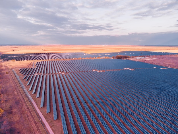 Vue aérienne de dessus d'une centrale de panneaux solaires panneaux solaires photovoltaïques au lever et au coucher du soleil à