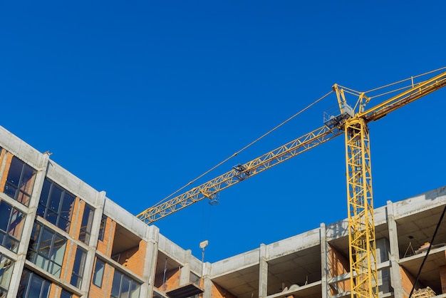 Vue aérienne de dessus du chantier de construction nouvelle grue à tour de bâtiments à plusieurs étages dans un immeuble de grande hauteur inachevé avec des grues de levage