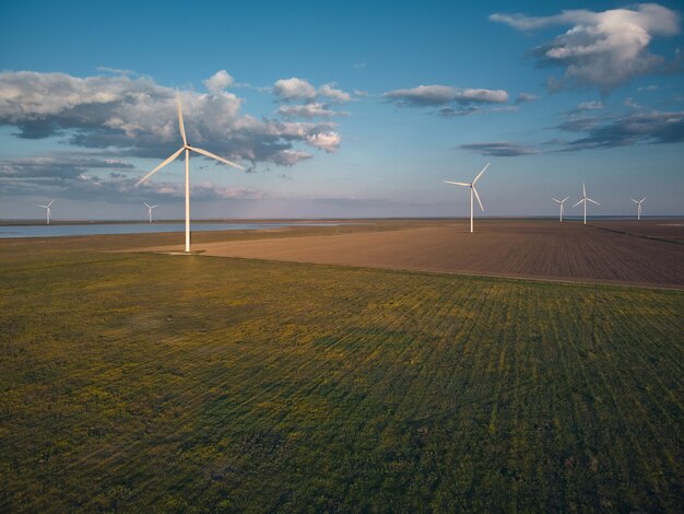 Vue aérienne de dessus des éoliennes et du champ agricole près de la mer au coucher du soleil