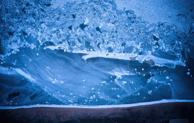 Vue aérienne de dessus des glaciers de mer gelés à la plage de la banquise fissurée dans l'océan en hiver