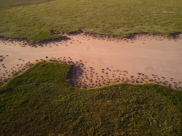 Vue aérienne de dessus d'herbe verte autour d'un ravin de sable formé par la pluie