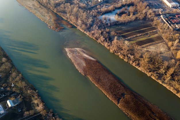 Vue aérienne de dessus, panorama de la campagne de petite île avec de l'herbe sèche dans une rivière calme sur une journée ensoleillée. Photographie de drone.