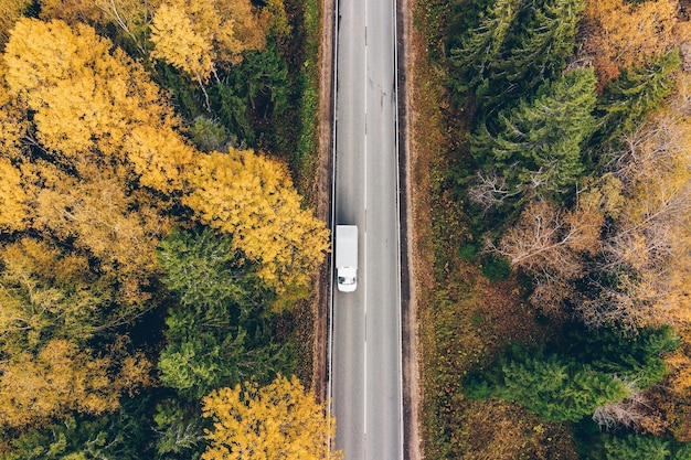 Vue aérienne de dessus de route avec voiture à travers la forêt d'automne avec des feuilles colorées