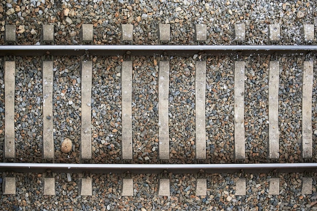Vue aérienne et détaillée des voies ferrées construites en métal et entourées de pierres à utiliser comme arrière-plan