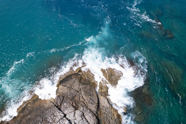 Vue aérienne Drone caméra de haut en bas des rochers du bord de mer dans un océan bleu Surface de la mer turquoise Incroyables vagues de la mer se brisant sur les rochers paysage marin Image de haute qualité des vagues de la mer à Phuket en Thaïlande