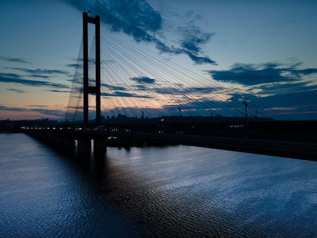 Vue aérienne d'un drone sur un pont à haubans sur une rivière dans une grande ville le soir