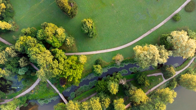 Vue aérienne de drone d'un pré vert dans un parc avec des chemins de terre et un lac