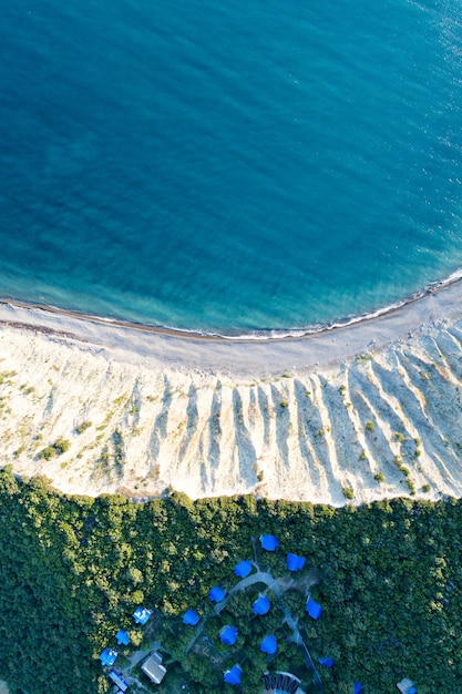 Vue aérienne du bord de mer vide avec du sable blanc et des chalets en bois