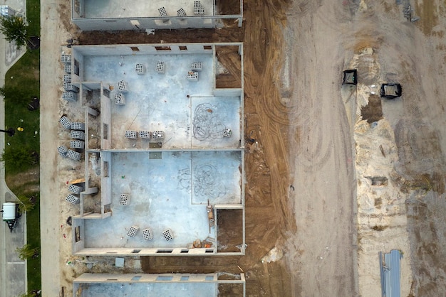 Vue aérienne du cadre inachevé d'une maison privée avec des murs en béton de brique prêts pour le montage de poutres de toit en bois en construction