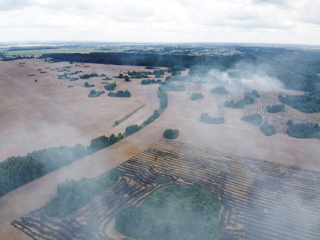 Vue aérienne du champ en feu avec de la fumée dans les terres agricoles