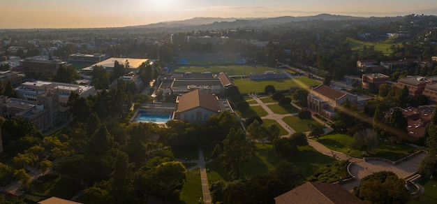 Vue aérienne du coucher de soleil du campus de l'UCLA avec une verdure luxuriante, une architecture diversifiée et des lieux de loisirs