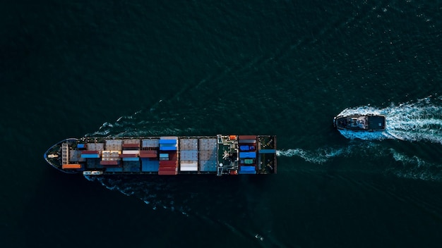 Vue aérienne du dessus du cargo porte-conteneurs et du remorqueur à pleine vitesse