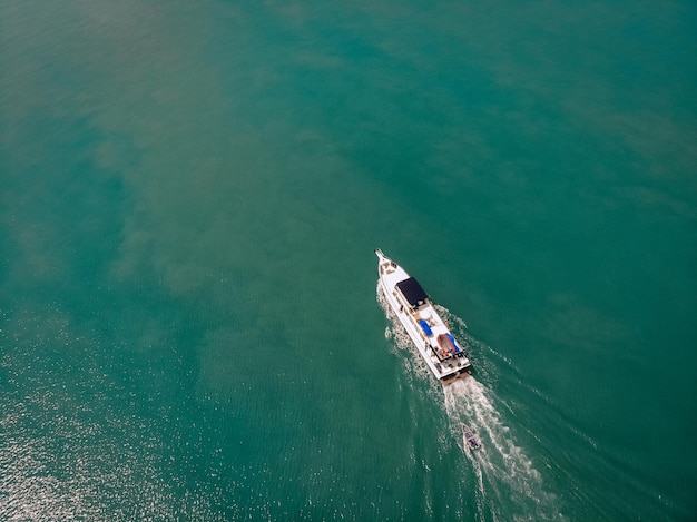 Vue aérienne du hors-bord et d'un bateau derrière lui naviguant près de la côte thaïlandaise, trace blanche sur l'eau ; concept de navires.