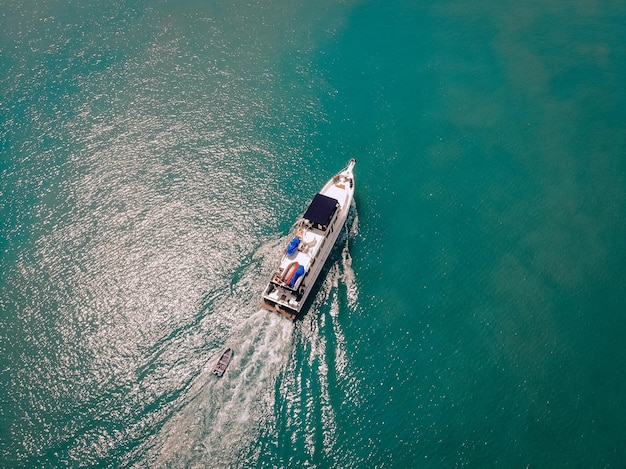 Vue aérienne du hors-bord et d'un bateau derrière lui naviguant près de la côte thaïlandaise, trace blanche sur l'eau ; concept de navires.