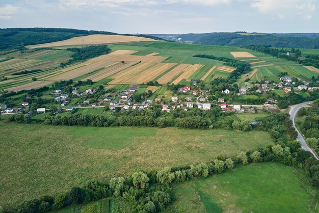 Vue aérienne du paysage des maisons de village et des champs agricoles cultivés verts lointains avec des cultures en croissance par une belle journée d'été