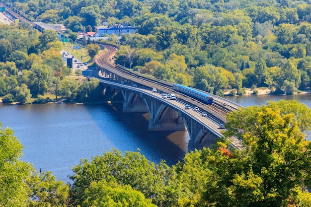 Vue aérienne du pont du métro avec le passage d'une rame de métro et le fleuve Dniepr à Kiev Ukraine Paysage urbain de Kyiv