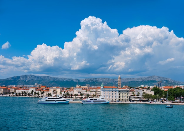 Vue aérienne du port de la ville de Split. Mer, navires à passagers, maisons historiques, tour avec des montagnes derrière