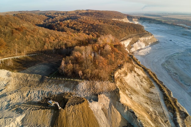 Vue aérienne du site minier à ciel ouvert de matériaux calcaires pour l'industrie de la construction avec des excavatrices et des camions à benne basculante