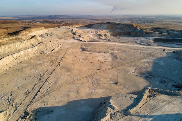 Vue aérienne du site minier à ciel ouvert de matériaux calcaires pour l'industrie de la construction avec des excavatrices et des camions à benne basculante