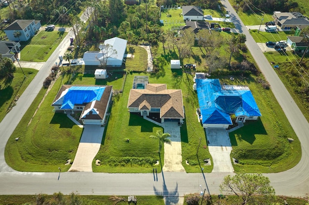 Vue aérienne du toit de la maison endommagée par l'ouragan Ian recouvert d'une bâche de protection bleue contre les fuites d'eau de pluie jusqu'au remplacement des bardeaux d'asphalte