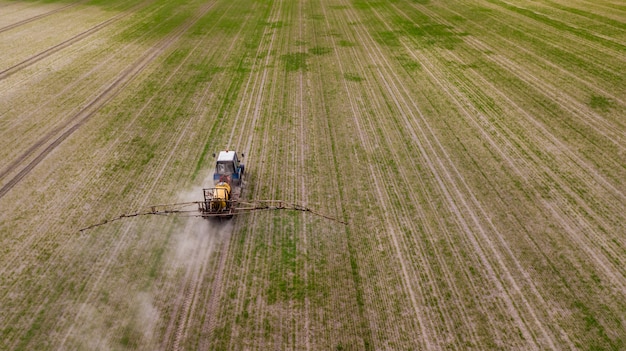 Vue aérienne du tracteur agricole labourant et pulvérisant sur le terrain