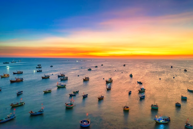 Photo vue aérienne du village de pêcheurs de mui ne au coucher du soleil avec des centaines de bateaux ancrés pour éviter les tempêtes