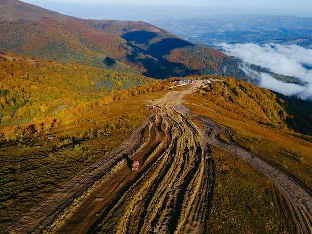 Vue aérienne du voyage hors route suv grimpant par l'espace de copie de la colline de la montagne saison d'automne au-dessus des nuages