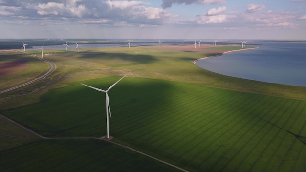 Vue aérienne des éoliennes et du champ agricole près de la mer au coucher du soleil