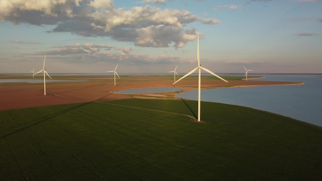 Vue aérienne des éoliennes et du champ agricole près de la mer au coucher du soleil