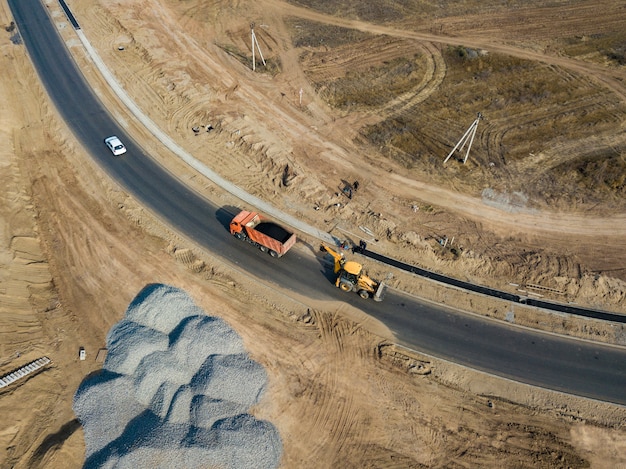 Vue aérienne de l'excavatrice industrielle a mis de l'asphalte dans la benne pour réparer la route