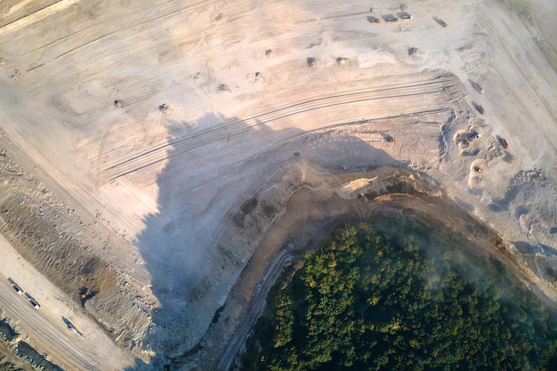 Vue aérienne de l'exploitation minière à ciel ouvert de matériaux calcaires pour l'industrie de la construction avec des excavatrices et des camions à benne basculante