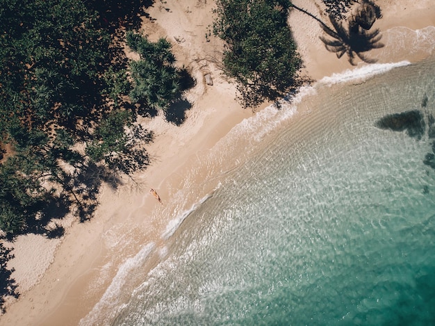 Vue aérienne de la femme allongée sur la plage. Jeune femme sur la mer. Phuket. Thaïlande. Vue de dessus. Paysage marin avec fille au bord de la mer, eau bleue et vagues. Voyager