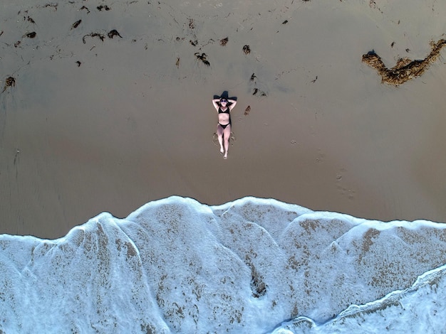 Photo vue aérienne d'une femme se détendant sur le rivage de la mer à la plage
